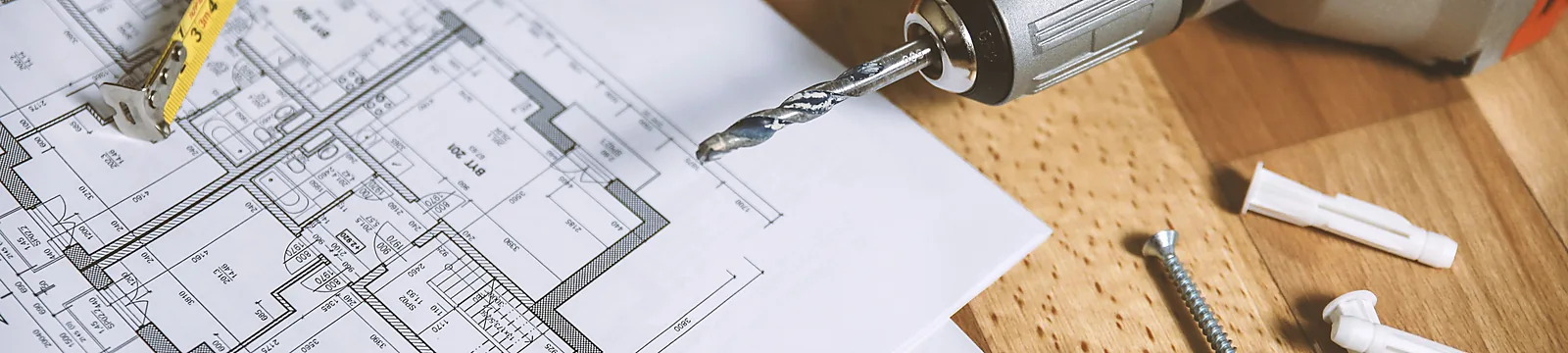 Grundriss, Maßband und Werkzeug auf einem Arbeitstisch